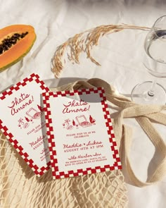 two red and white cards sitting on top of a table next to some wine glasses