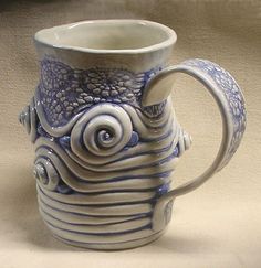 a blue and white coffee mug with swirly designs on the outside, sitting on a table