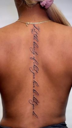 the back of a woman's neck with tattoos on it and words written in cursive writing