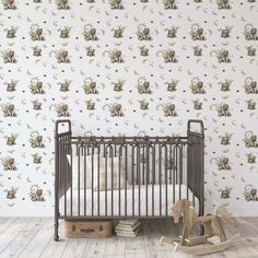 a baby crib in front of a wallpapered nursery