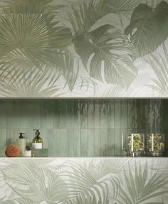 the bathroom is decorated with green tiles and palm leaves on the wall, along with soaps and lotions