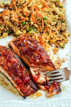 two salmon fillets on a plate with rice and vegetables