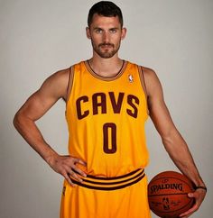 a man holding a basketball in his right hand and wearing a yellow uniform with the number 0 on it