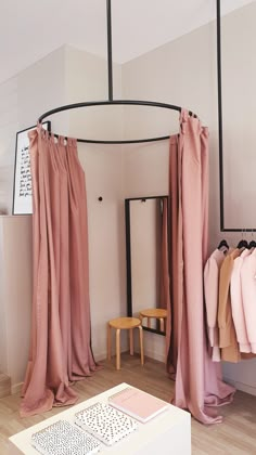 a room with pink curtains and clothes on hangers