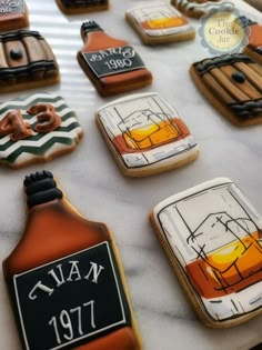 decorated cookies are on a table with bottles and labels for various types of alcohols