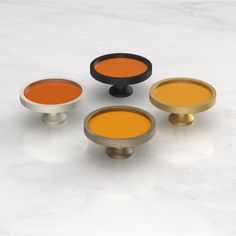 four different colors of knobs on a white surface with one orange and one red