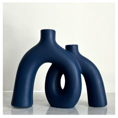 two blue vases sitting next to each other on a white counter top in front of a wall