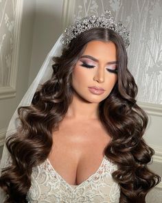 a woman with long hair wearing a wedding dress and tiara is posing for the camera