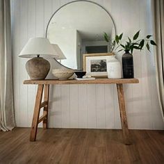 a wooden table topped with a lamp next to a mirror