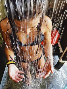 a woman is standing in the rain with her hands on her hips and water pouring over her head