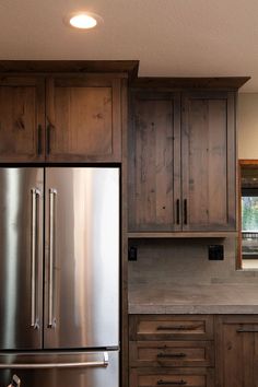 a stainless steel refrigerator and wooden cabinets in a kitchen