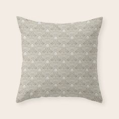 a beige pillow with white flowers on the front and back, against a gray background