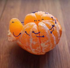 an orange with faces drawn on it sitting on top of a wooden table next to a quote