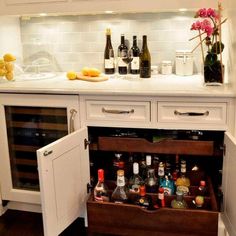 an open cabinet filled with liquor bottles in a kitchen