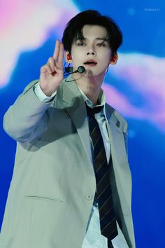 a young man in a suit and tie making the v sign with his hand while standing on stage