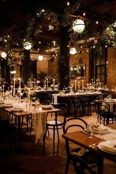 tables and chairs are set up for an event with lights hanging from the ceiling above them