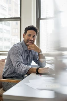 a man sitting at a desk in front of a laptop computer with his chin resting on his hand