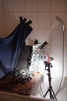 a camera is shooting water out of a shower head and onto a wooden table with a blue sheet on it