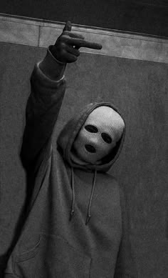 a person wearing a mask pointing at something with one hand and the other finger in the air