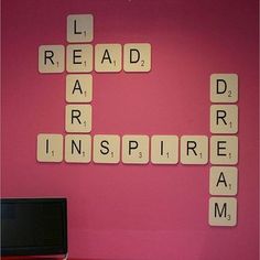 scrabble tiles spelling out words on a pink wall with a laptop and keyboard