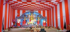 an indoor stage with red and white stripes on the walls, decorated with statues of hindu deities