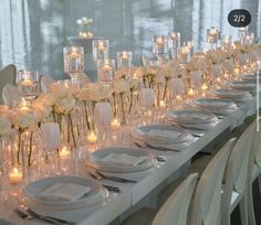 a long table is set with white flowers and candles for an elegant dinner or reception