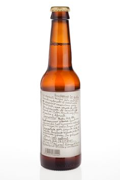 a brown beer bottle with writing on the side and a corked top, in front of a white background