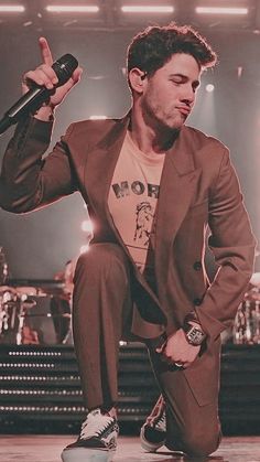 a man sitting on top of a skateboard in front of a stage holding a microphone