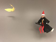 an elf is standing next to a bird on a gray surface with gold foil flying above it