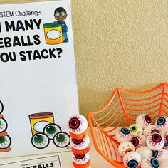 an orange basket filled with fake eyeballs next to a sign that says, i may reballs you stack?