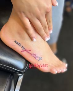 a woman's foot with the words walk by faith written on her left side