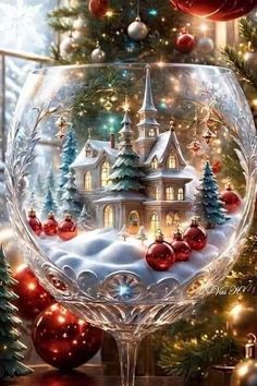 a christmas scene in a wine glass with ornaments on the table and a tree behind it