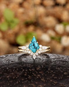 a turquoise and white stone ring sitting on top of a rock