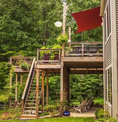 a house in the woods with a deck and stairs leading up to it's second story