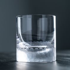 a shot glass filled with lots of rocks on top of a wooden table in front of a dark background