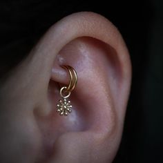 a close up of a person's ear with a gold nose ring