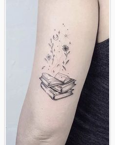 a woman's arm with a tattoo on it that has an open book and stars flying