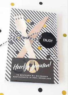 a black and white striped gift wrapper with gold confetti on it that says, enjoy