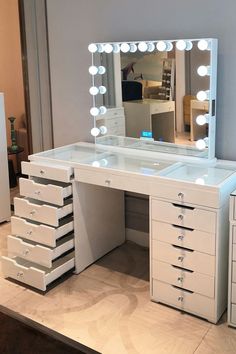 a white vanity with drawers and lights on the top shelf in front of a mirror