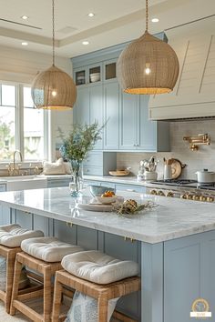 a large kitchen with blue cabinets and white counter tops, two hanging lights above the island