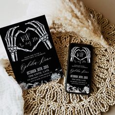 two black and white wedding stationery with skeleton hand prints on them, next to a pair of cell phones