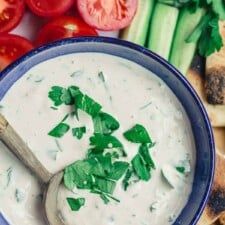 a blue bowl filled with dip surrounded by vegetables