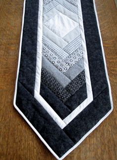 a black and white quilted necktie on a wooden table with wood flooring