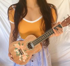 a woman holding an ukulele with flowers on it