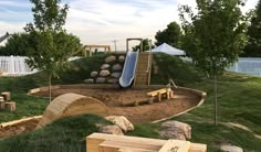 there is a play area in the yard with wooden benches and slides on top of it