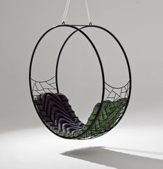 a hanging chair that is made out of metal and has green fabric on the back