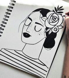 a drawing of a woman's face with flowers in her hair, on top of a notebook