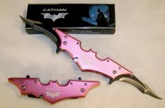 two pink and silver batman knives next to a box