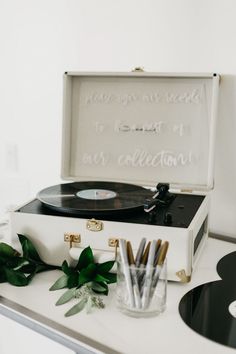 a record player sitting on top of a table next to a glass and pen holder