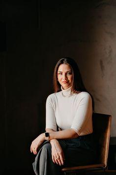 a woman sitting in a chair with her arms crossed and looking off to the side